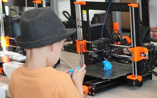 boy looking at an object made on a three-dimensional printer