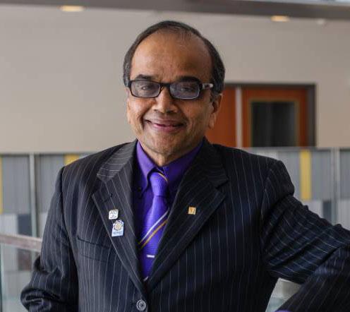 man in suit and tie, with glasses, smiling